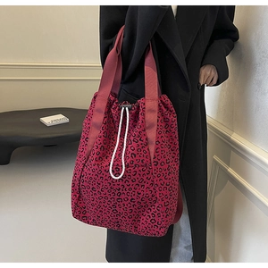 Detail of red leopard print tote bag with drawstring closure and wide shoulder strap