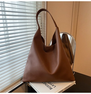 Macro shot of brown pebble grain leather tote bag showing soft texture and shoulder strap