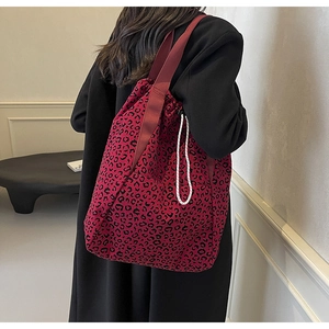 Detail of red leopard print tote bag with drawstring closure and wide shoulder strap