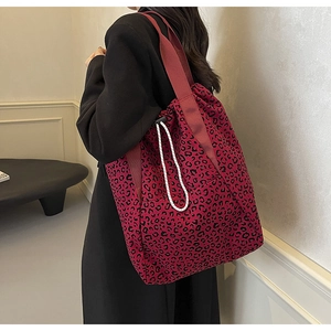 Woman carrying a red leopard print canvas tote bag with black drawstring details