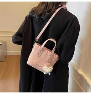 Detailansicht der rosa Eimer-Tasche mit Marmormuster, Goldschnalle und Plüsch-Anhänger