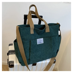Detail of dark green corduroy tote bag showing large side pockets and hand straps