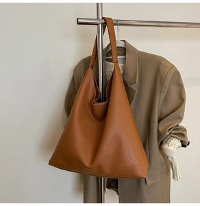 Close-up of brown litchi pattern leather tote bag hanging with autumn aesthetic clothing