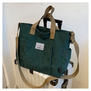 Macro detail of dark green corduroy fabric texture and khaki canvas straps on a tote bag