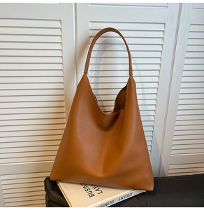 Detail of caramel brown hobo bag with pebble leather texture on minimalist background