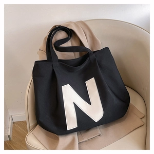 Close-up of high-density black canvas tote bag featuring a large white N letter design