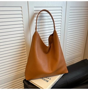Close-up of brown pebbled leather tote bag with V-shaped opening and wide shoulder strap