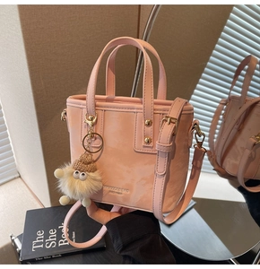 Detailansicht der rosa Eimertasche aus Kieselleder mit goldener Hardware und Monster-Anhänger
