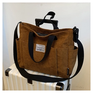 Brown corduroy tote bag detail showing the luggage handle sleeve for travel use