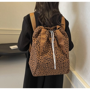 Detailed view of leopard print canvas backpack with white drawstring and adjustable buckles
