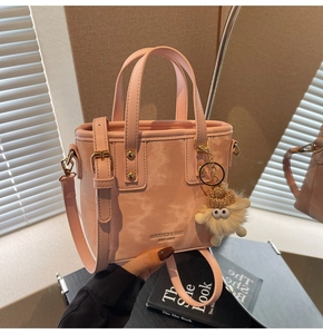 Detailaufnahme der rosa Eimertasche mit flauschigem Plüsch-Anhänger und Hardware-Details