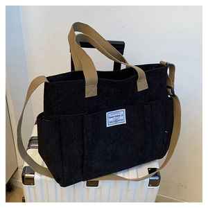 Detailed view of black corduroy tote bag with functional pockets and khaki webbed handles