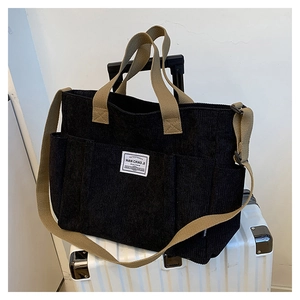 Detail of black corduroy tote bag with multiple pockets and khaki canvas straps