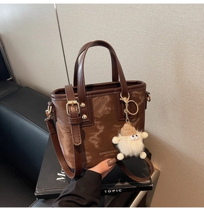 Detailansicht der braunen Bucket Bag mit Marmormuster und Plüschmonster-Anhänger
