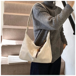 Detail of white leather shoulder bag with brown woven accent and gold hardware