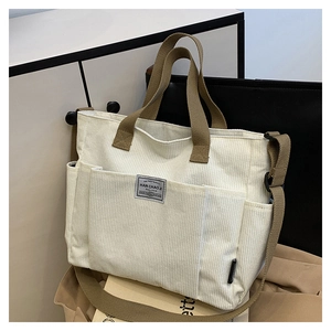 Detail of cream corduroy tote bag with brown canvas handles and front pocket