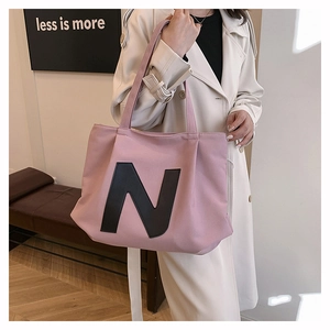 Detailed view of pink canvas tote bag showing the bold letter N and spacious interior design