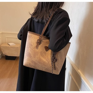Sac cabas vintage marron porté par un mannequin avec logo triangulaire et pompon