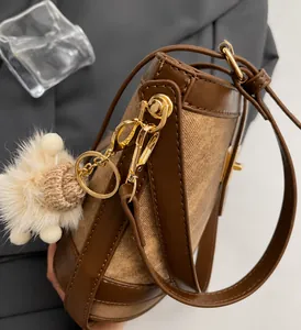 Detail of premium golden hardware and plush pendant on a brown bucket handbag