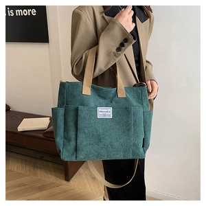 Detail of dark green corduroy shoulder bag showing multi-pocket structure and soft texture