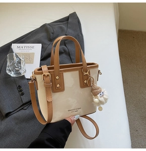 Detail einer minimalistischen creme Tasche mit braunem Rand und Plüsch-Anhänger
