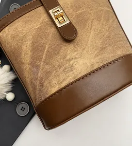 Close-up of brown vintage bucket bag showing leather stitching and gold twist lock