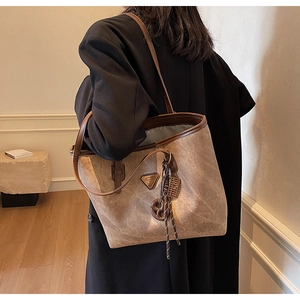 Gros plan d'un sac cabas marron vintage avec emblème en métal et détail de sangle tissée