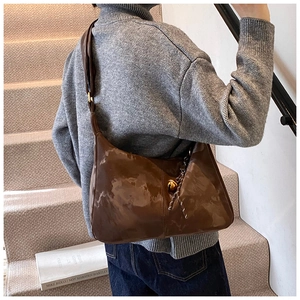 Detail view of deep brown crescent bag with glossy texture and metal ball closure