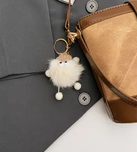 Detail of creative plush charm with knit hat and gold clasp on a luxury leather bucket bag