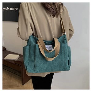 Detail of teal corduroy tote bag showing textured fabric and khaki straps on a model