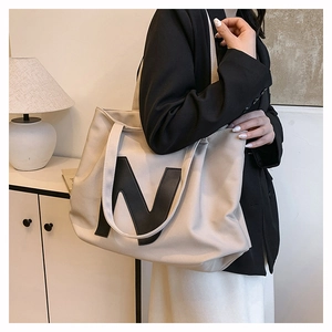 Detailed view of a beige canvas tote bag with black N patch on a female model