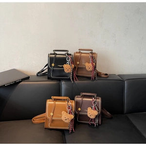 Detail of four retro PU leather backpacks with plush bear charms and lattice ribbons