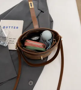 Detail view of the spacious brown bucket bag interior holding a wallet and umbrella