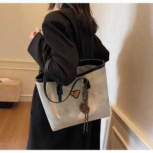 Vue latérale du grand sac cabas gris texturé avec bandoulières noires et logo en métal