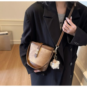 Detail of vintage bucket bag with metal twist lock and cute lamb wool pendant on model