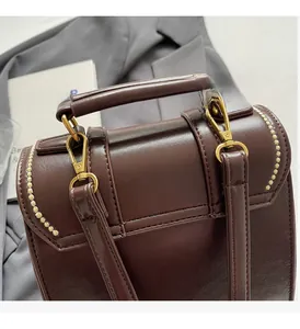 Detail of dark brown PU leather bag featuring gold D-rings and fine stitching accents
