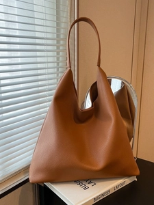Brown leather hobo tote bag with lychee texture displayed on a minimalist table