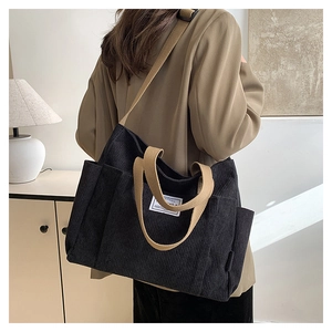 Detail of black corduroy tote bag with khaki straps showing side pocket and side profile