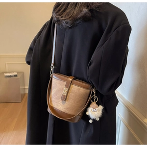 Close-up of vintage brown bucket bag with gold twist lock and plush monster charm