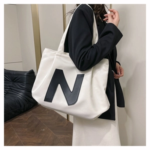 Detail shot of canvas tote bag featuring large black N logo with model upper body view