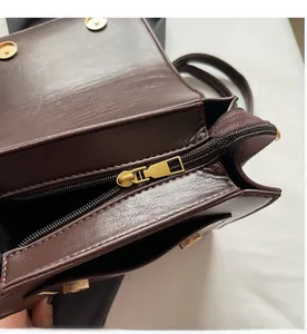 Detail view of smooth zipper and golden magnetic closure on dark brown leather backpack