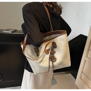 Vue détaillée du grand sac cabas en toile beige avec sangles en cuir marron et logo