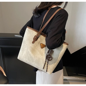 Détail du sac cabas en toile avec bandoulières en cuir marron et logo métallique