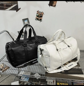 Détail de sacs de voyage en similicuir noir et beige avec slogan Believe in Yourself