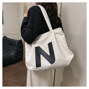 Detailed side view of the large white canvas tote bag with a bold black letter N design
