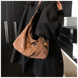 Detail of brown vintage leather hobo bag with woven rope and golden bell ornament