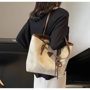 Détail du sac cabas en toile avec garniture en cuir marron et plaque logo en métal