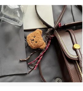 Detail view of a vintage dark brown leather crossbody bag with cute plush bear charm
