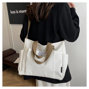 Detail of white corduroy tote bag with brown straps and functional side pockets