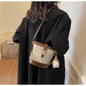 Detail of canvas bucket bag with brown leather trim and golden metal turn-lock